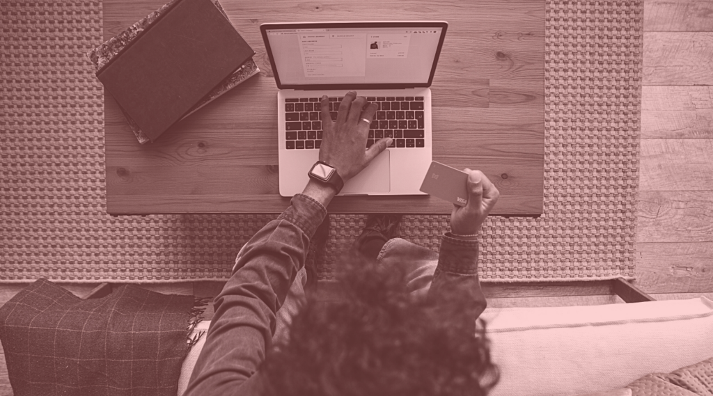 Overhead view of person in front of open laptop with one hand on the keys.